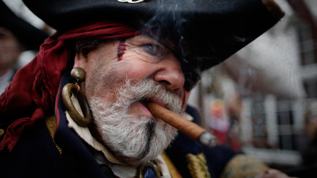 Bearded man in pirate costume with cigar between lips